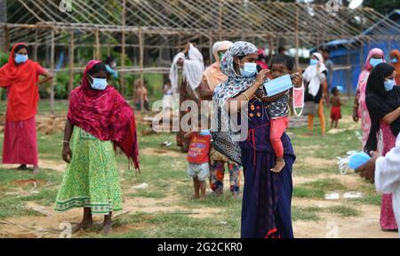 Bengaluru, India. 10 Giugno 2021. Una madre mette una maschera facciale sul suo bambino mentre attende in coda con altri rifugiati Rohingya per razioni nel loro campo di Jakkur. Anche se la gente ha intenzione di aiutare, non è possibile senza l'aiuto dei donatori dice il Dott. Shama Shareef che ha aiutato i rifugiati di Rohingya/Banjara/Bangladesh con razione di approvvigionamento su base regolare. Archana Lemanja Tomar ha colloato con GOONJ Bengaluru verso il drive di distribuzione giovedì a Bengaluru. (Foto di Meghana Sastry/SOPA Images/Sipa USA) Credit: Sipa USA/Alamy Live News Foto Stock