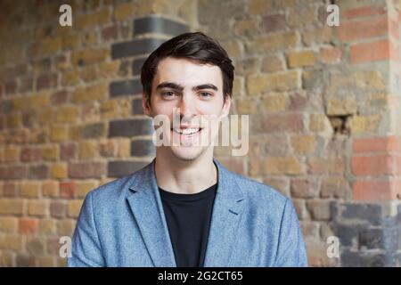 Ritratto di giovane uomo contro un muro di mattoni Foto Stock