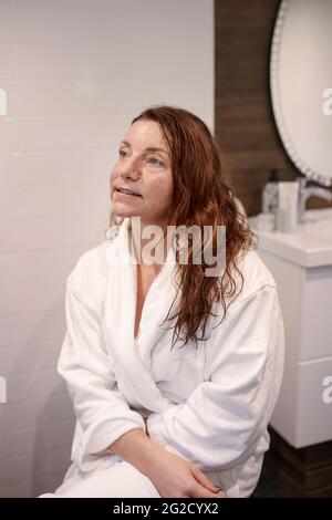 Donna seduta nella stanza da bagno Foto Stock
