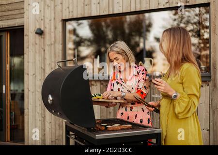 Sorridente amiche che preparano il cibo al barbecue Foto Stock