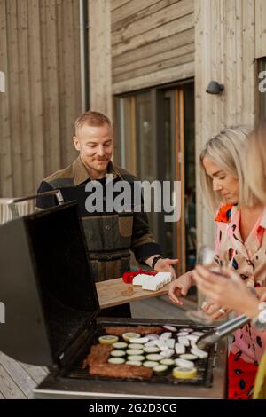 Amici che preparano il cibo al barbecue Foto Stock