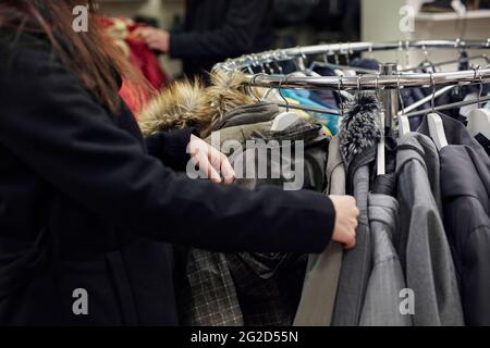 Donna che guarda giacche in negozio di abbigliamento Foto Stock