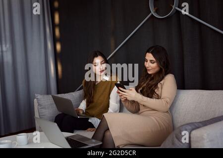 Donne che si siedono sul divano Foto Stock
