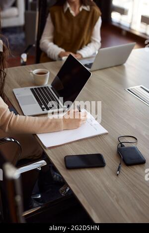 Donna che prende appunti durante la riunione di affari Foto Stock