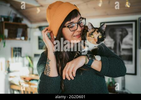 Giovane donna che porta il gatto sulla spalla Foto Stock