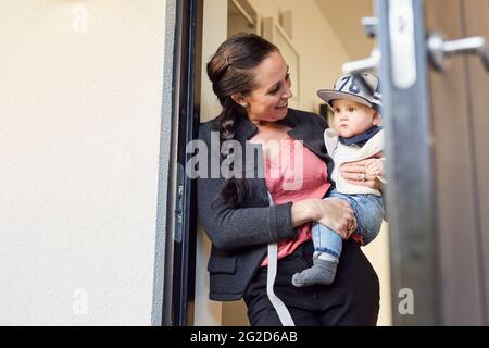 Donna sorridente che porta il figlio del bambino Foto Stock
