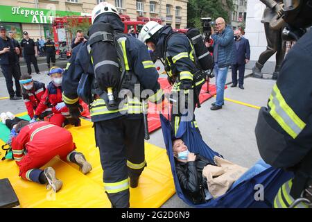 KHARKIV, UCRAINA - 10 GIUGNO 2021 - i vigili del fuoco trasportano una persona durante le esercitazioni tattiche speciali del servizio di emergenza di Stato fuori di un shop locale Foto Stock