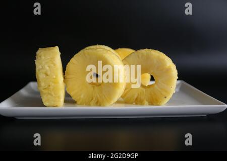 Freschi isolati gustosi ananas a fette nella piastra bianca, concetto di numeri con cibo, 100 Foto Stock