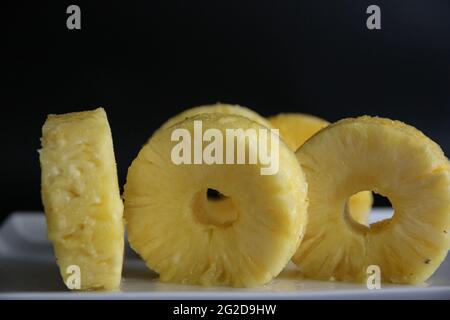 Freschi isolati gustosi ananas a fette nella piastra bianca, concetto di numeri con cibo, 100 Foto Stock