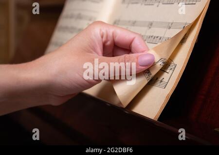 La mano del pianista gira pagina di musica di spartiti. Primo piano. Foto Stock