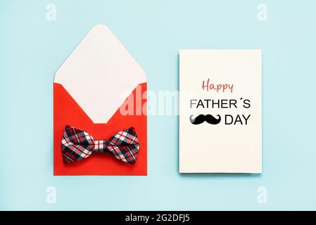 Buon giorno del Padre. Busta rossa con cravatta ad arco e carta bianca con il testo Happy Father's Day su sfondo blu Foto Stock