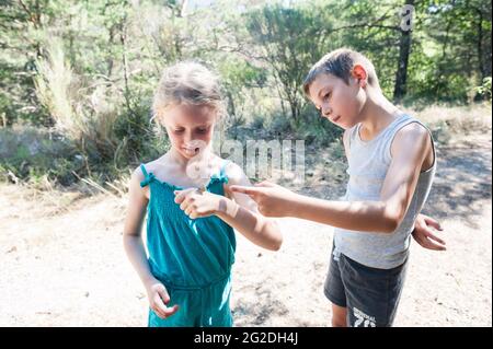 Una farfalla atterra su una mano di ragazze giovani mentre è fuori per una passeggiata nella natura. Foto Stock