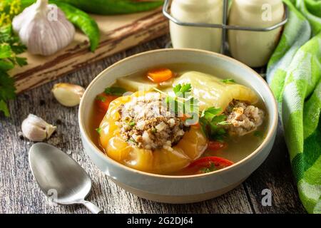 Cibo sano, dieta del keto, pranzo. Peperone con carne e bulgur in brodo con verdure in una ciotola su un tavolo rustico. Foto Stock