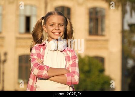 stile casual per bambina all'aperto. le vacanze di primavera sono appena iniziate. la sua playlist estiva preferita. i bambini ascoltano la musica. i bambini sorridono ascoltando il libro audio Foto Stock