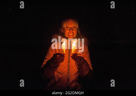 Una donna tiene due candele nell'oscurità Foto Stock