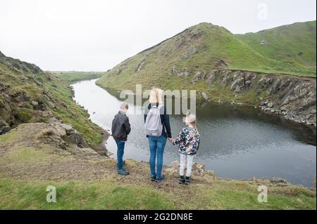 Una madre si leva in piedi con i suoi capretti che guardano un corpo di acqua e colline nello Shropshire Inghilterra Foto Stock