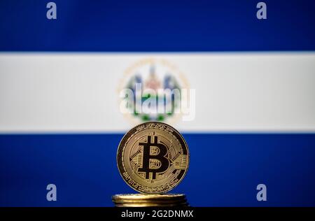 Moneta di rappresentanza Bitcoin posta di fronte alla bandiera nazionale offuscata di Salvador. El Salvador è il primo paese ad adottare il bitcoin come valuta legale. Co Foto Stock