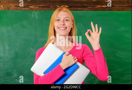 Ritorno a scuola. Istruzione. Sorridente insegnante in classe mostra segno ok. Università. College. Foto Stock