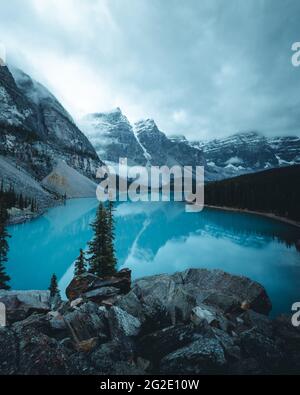 Lago di Moraine durante la calma mattina con neve fresca polvere sulla cima di montagne. Scarafaggi canadesi. Montagne Rocciose Viaggi Alberta Foto Stock