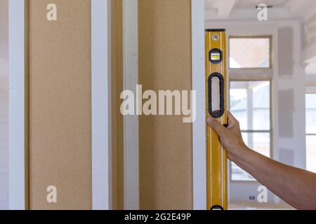 Operatore che utilizza uno strumento di livellamento controllare le colonne di legno appropriate utilizzando il livello Foto Stock
