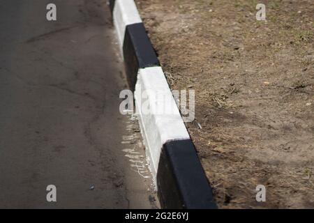 Bordo contrassegnato. Marciapiede verniciato bianco e nero. Segnaletica stradale per i conducenti. Notevole colorazione del cordolo. Foto Stock