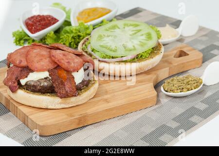 Fetta di panino hamburger con salame, carne e salsa; pronto per l'assemblaggio del Burger. Foto Stock