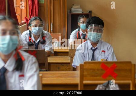 BALI, INDONESIA-MAGGIO 18 2021: Gli studenti in Indonesia stanno seguendo il processo di apprendimento in classe utilizzando faceshield e maschere di salute per implementare la salute p Foto Stock