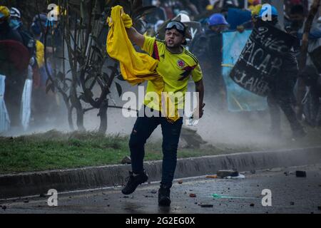 Un dimostratore grida e protesta con una bandiera della nazionale colombiana mentre le manifestazioni si intensificavano a disordini e scontri tra dimostranti e la polizia malata colombiana diffamano manifestazioni anti-governative contro il presidente della Colombia Ivan Duque, la brutalità e le disuguaglianze della polizia a Pato, Colombia, il 9 giugno 2021. Foto Stock