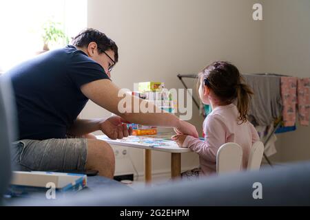 padre con bambina che gioca con puzzle a casa. Insieme attività del bambino e del genitore. Educazione domestica, concetto di scolarizzazione domestica. Giochi educativi Foto Stock