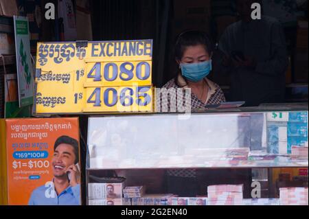 Una donna cambogiana, indossando una maschera protettiva / copertura in una cabina di cambio di denaro durante la pandemia di coronavirus. Mercato di Kandal, Phnom Penh, Cambogia. 25 Marzo 2020. © Kraig Lieb Foto Stock