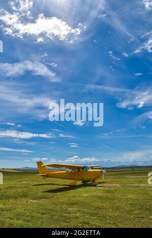 Piccolo aereo in piedi su un campo d'erba contro i Monti Tatra e cielo blu nuvoloso Foto Stock