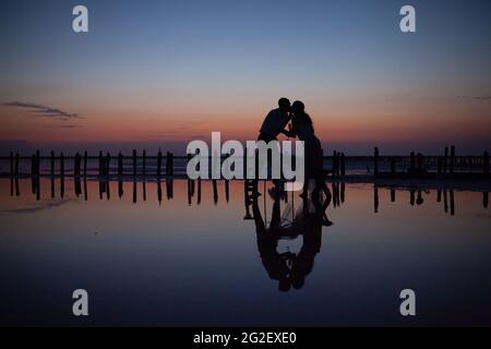 coppia di nozze amorevole al tramonto sul lago rosa Foto Stock