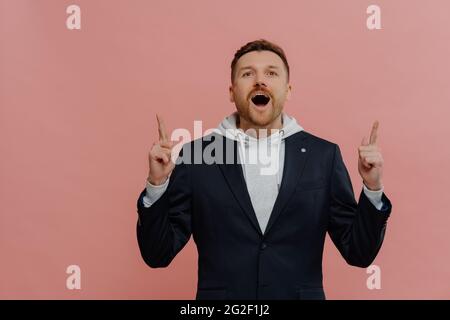 L'uomo zenzero stupito che punta in su con le dita di indice e l'espressione eccitata del volto Foto Stock