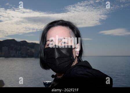 Donna vestita con maschera nera protettiva per proteggersi dalla pandemia di covidio. Foto Stock