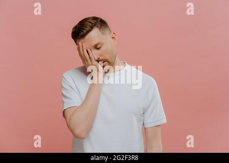 Giovane uomo caucasico esausto che posa su sfondo rosa Foto Stock