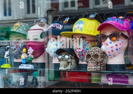 Maschere facciali in vendita in vetrina a Bournemouth, Dorset UK nel mese di giugno - teste mannequin che indossano cappellini da baseball e maschere facciali maschera Foto Stock