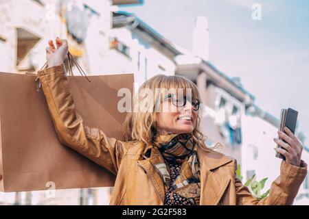 donna felice con borse aziendali e cellulare festeggiamenti Foto Stock