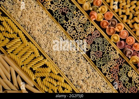 Un sacco di pasta cruda di diversi tipi e colori, divisa da spaghetti in celle uguali Foto Stock