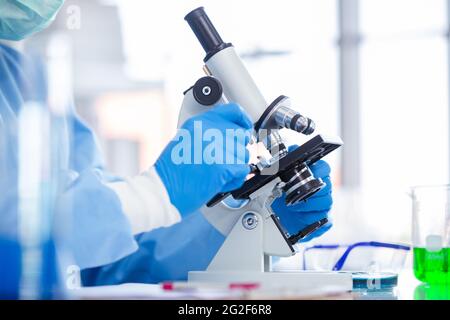 Closeup Scientist Dottore di lavoro in laboratorio sanitario medico per la ricerca medica guardando al microscopio. Scienza covid virus vaccino ricerca medica c Foto Stock