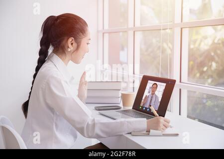 Donna che saluta la videochiamata con il medico dal canale di Internet che rimane a casa. Ragazza teen paziente in videoconferenza con medico di salute generale Foto Stock