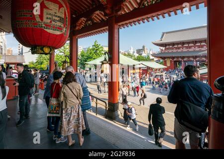 Tokyo, Giappone - 05.13.2019: Molte persone camminano verso l'edificio principale del complesso del tempio di Asakusa in una giornata di sole Foto Stock