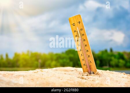 Termometro meteorologico nella sabbia contro il cielo che mostra una temperatura ambiente elevata Foto Stock