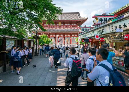 Tokyo, Giappone - 05.13.2019: Molte persone camminano verso l'edificio principale del complesso del tempio di Asakusa in una giornata di sole Foto Stock