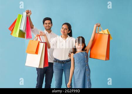 UNA FAMIGLIA FELICE IN POSA GIOCOSAMENTE DAVANTI ALLA FOTOCAMERA CON BORSE PER LA SPESA Foto Stock