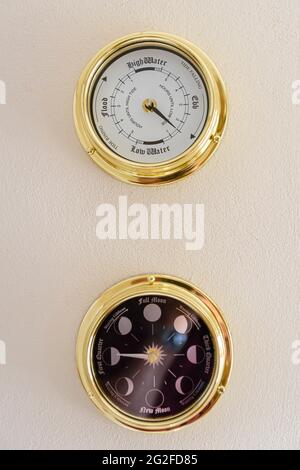 Orologio in ottone con marea e orologio di fase lunare su una parete Foto Stock