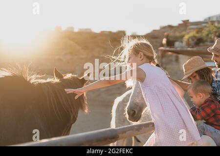 Buona famiglia che si diverte con i cavalli all'interno del ranch Foto Stock