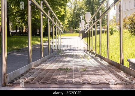 Accanto alle scale sono installate rampe metalliche con corrimano, un piano inclinato per sedie a rotelle e carrelli per un movimento confortevole. Foto Stock