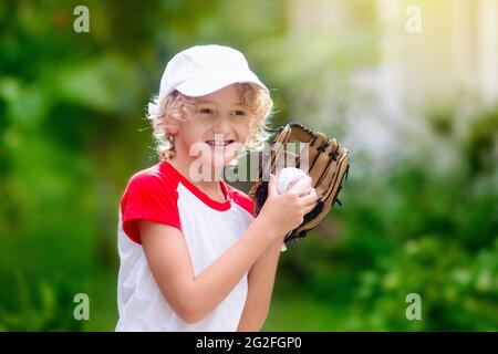 I bambini giocano a baseball. Bambino con pipistrello e palla. Attività all'aperto per bambini sani. Divertente gioco di palla di squadra per ragazzo e ragazza. Giovane atleta sul campo da baseball. Foto Stock