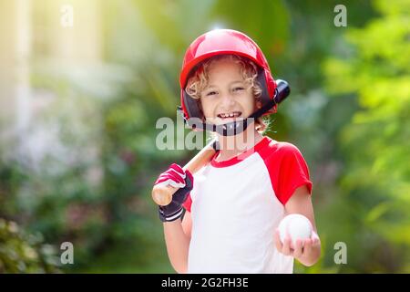 I bambini giocano a baseball. Bambino con pipistrello e palla. Attività all'aperto per bambini sani. Divertente gioco di palla di squadra per ragazzo e ragazza. Giovane atleta sul campo da baseball. Foto Stock