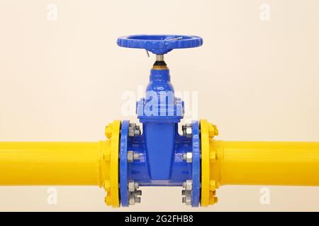 Tubazione con valvola. Tubo giallo con gru blu, industria petrolifera e del gas Foto Stock